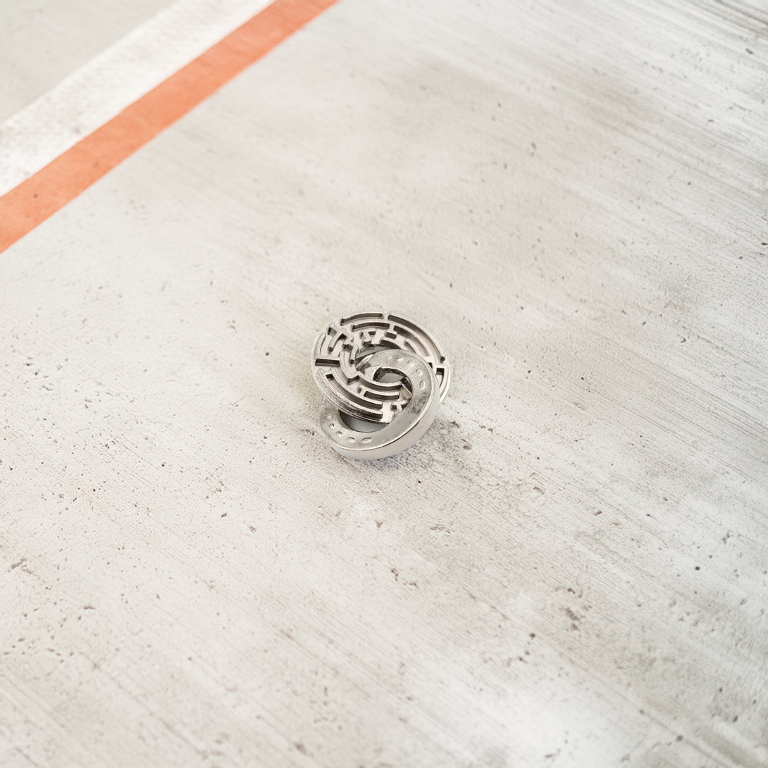 Rustic metal puzzle featuring two interlocked horseshoes and a central ring, showcasing a vintage steel finish with a challenging design.